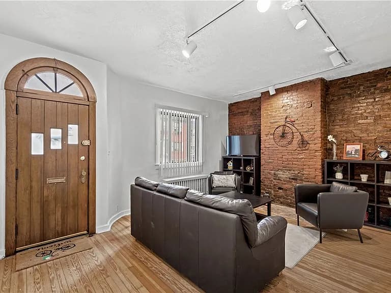 Living room listing photo showing the arched entry and exposed brick wall